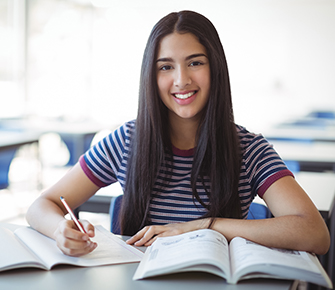 smiling girl student doing homework in class
