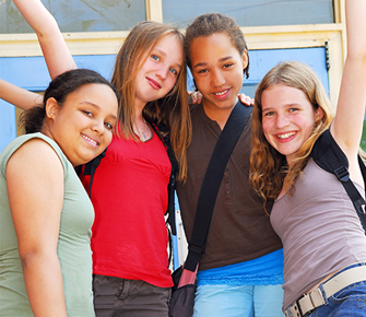 four smiling students with their hand in the air