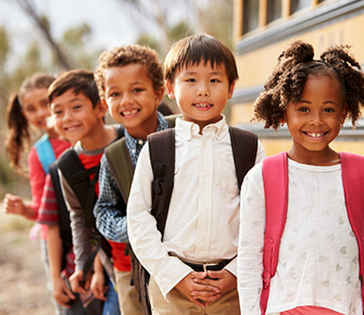 five students standing by a bus smiling