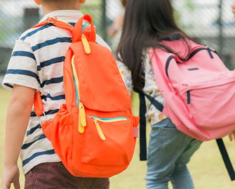 the back of two students wearing backpacks