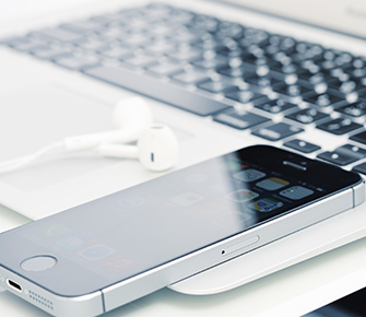 a phone and earbuds on top of a laptop